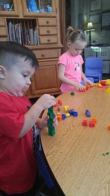 Two children playing with building blocks at a table