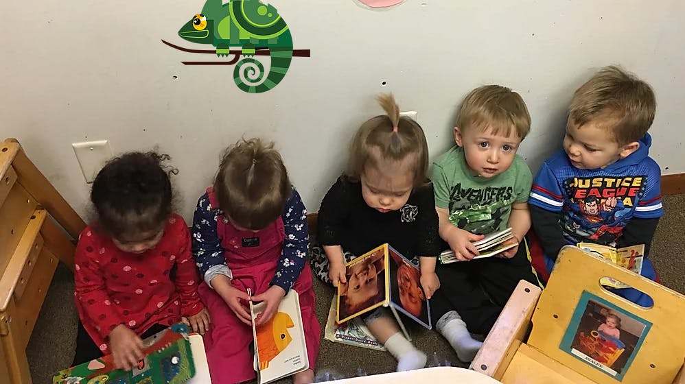 Five children sitting on the floor reading books