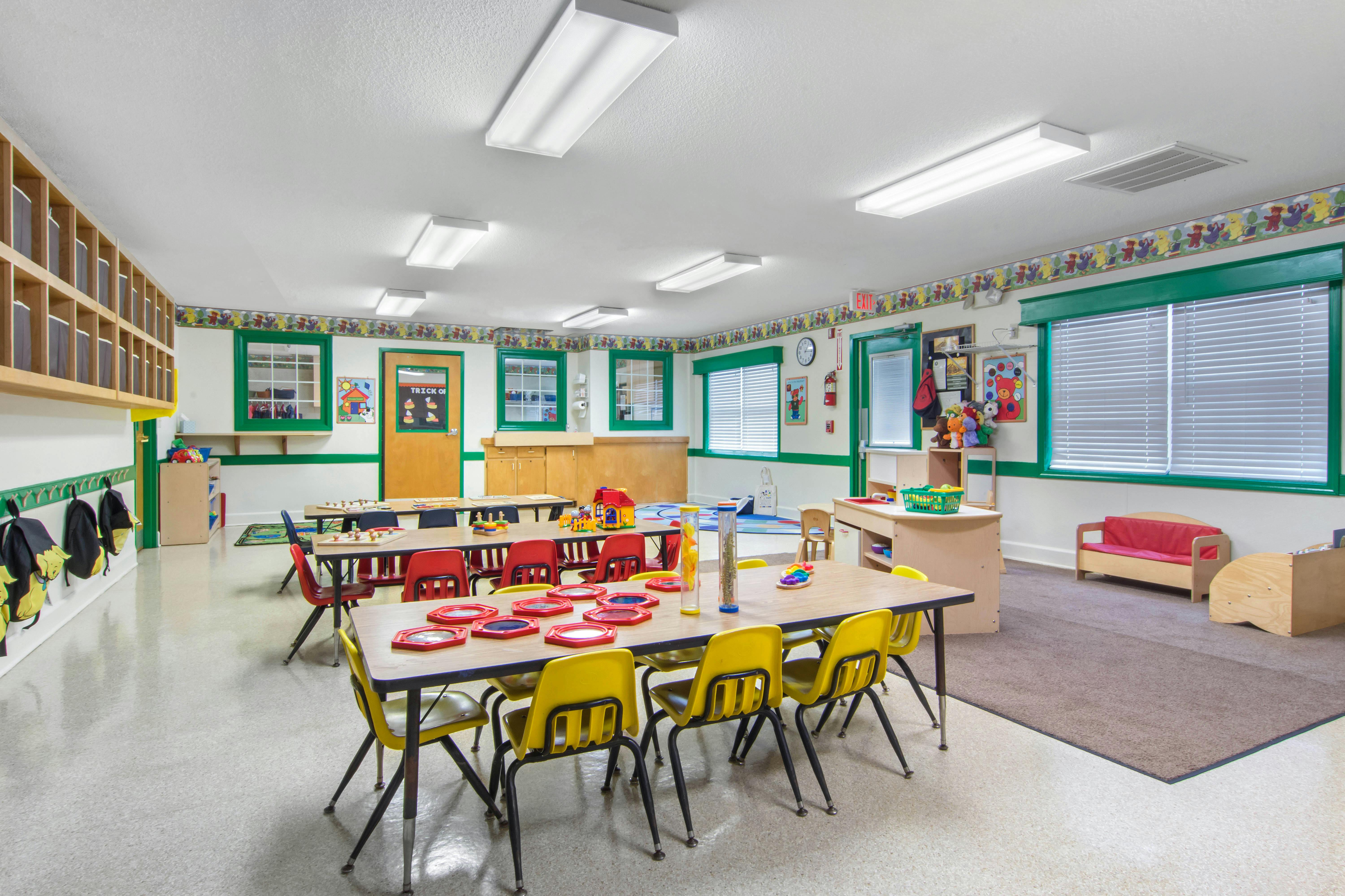 Classroom with children's tables and chairs, cubbies, and windows