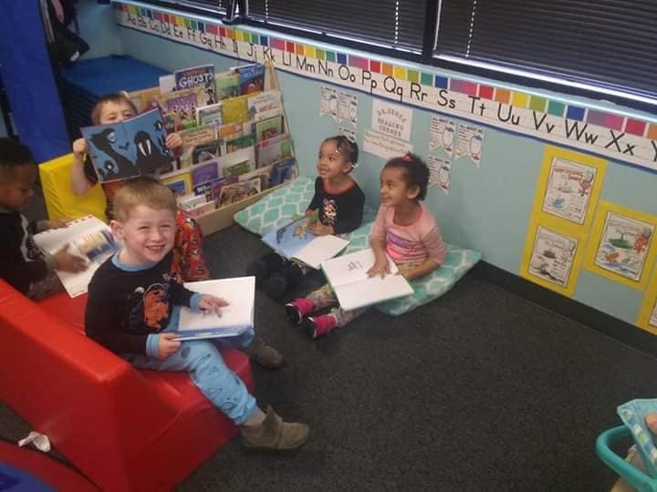 Children sitting on floor and red bench with books and papers