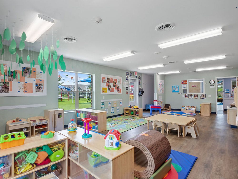 A colorful classroom with toys and furniture, a window overlooks a playground