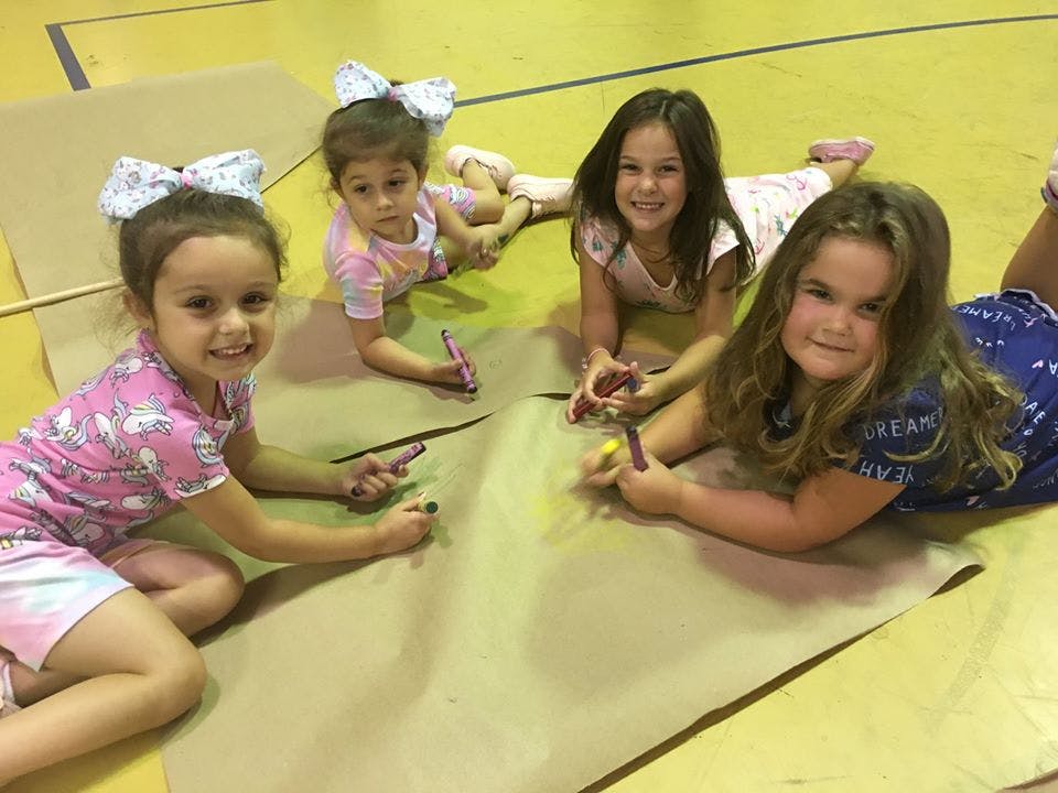 Four children drawing on paper on the floor