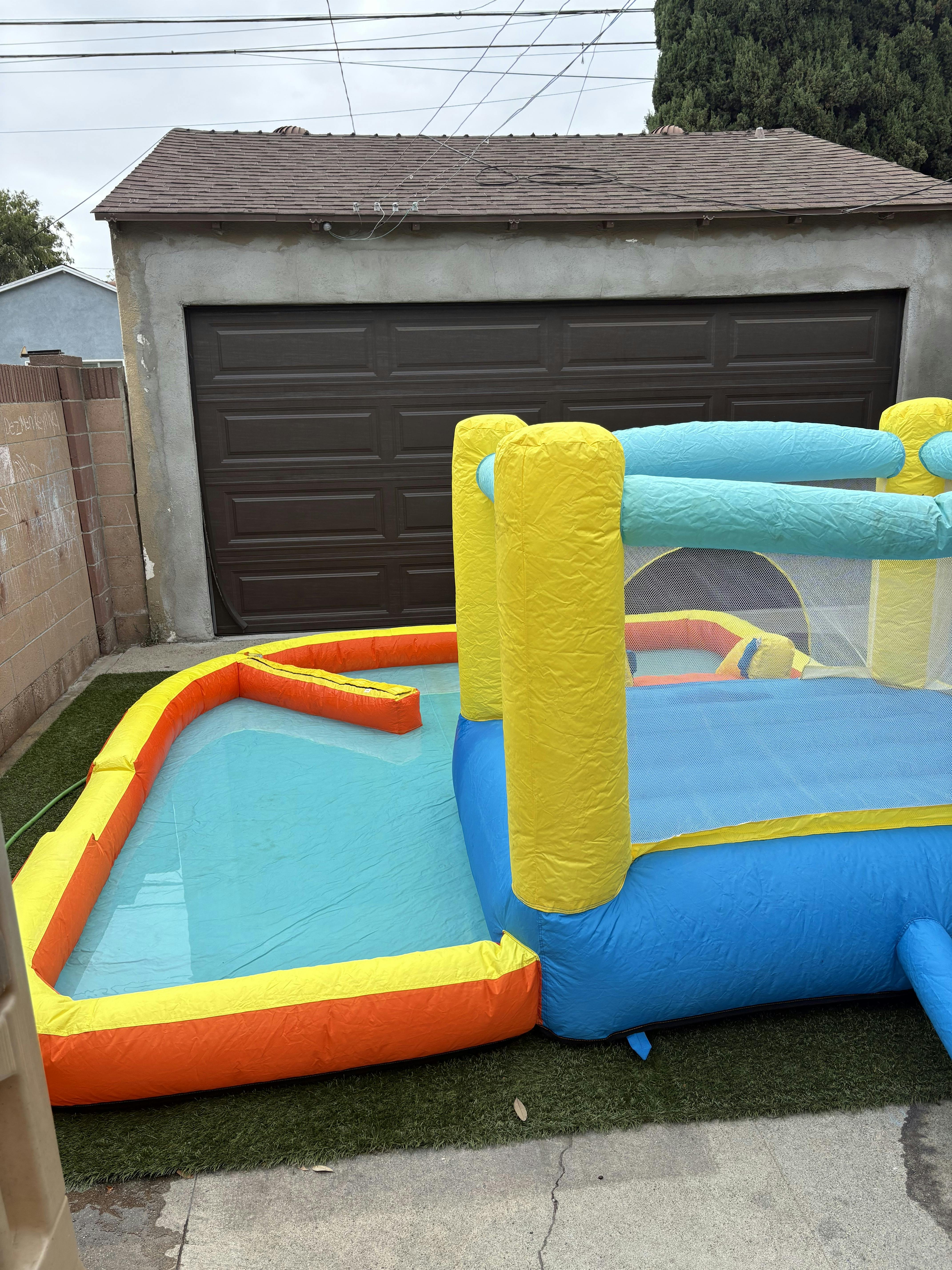 Inflatable bounce house with attached water pool in a residential backyard