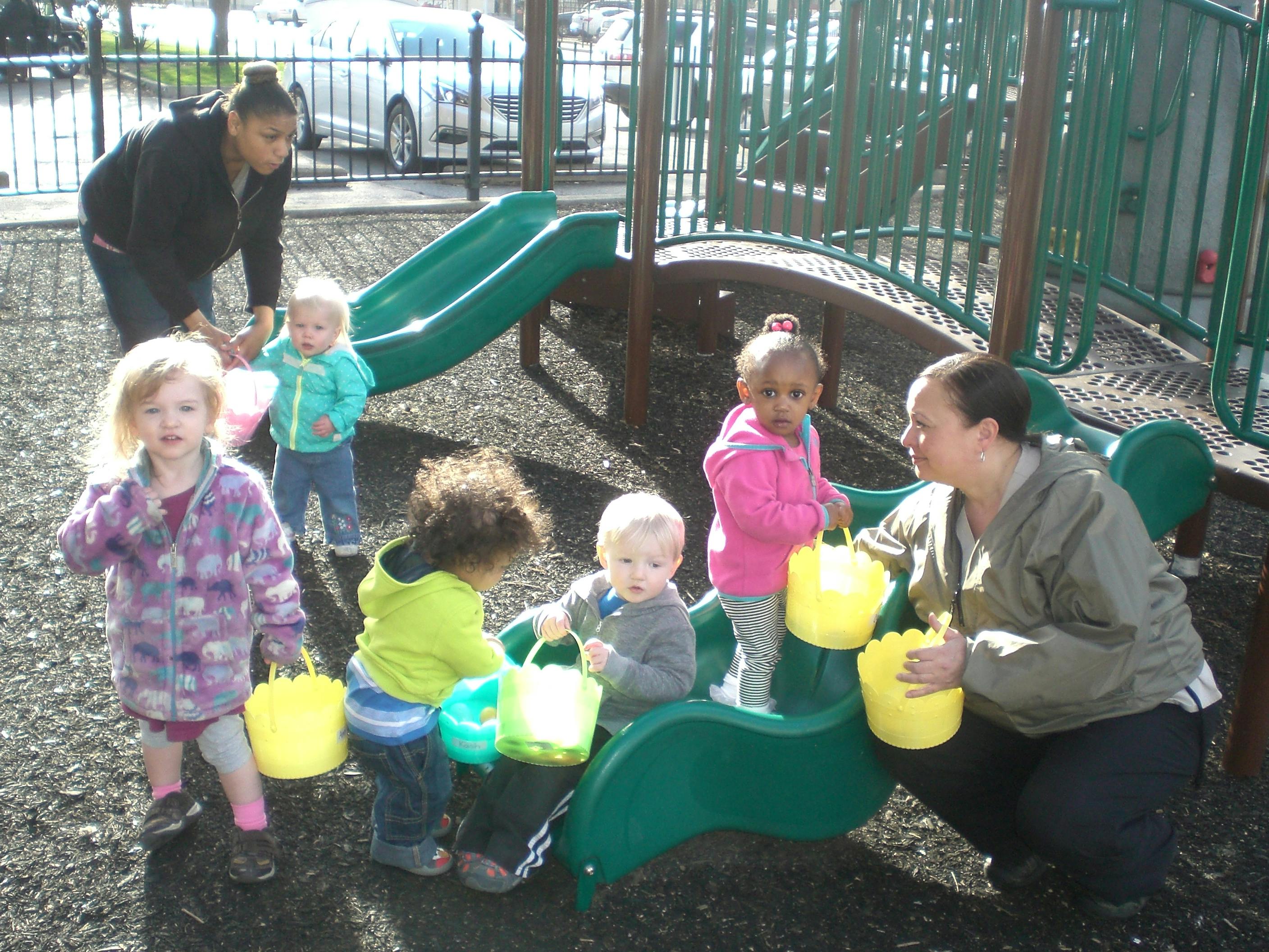 Adults and children with buckets on a playground