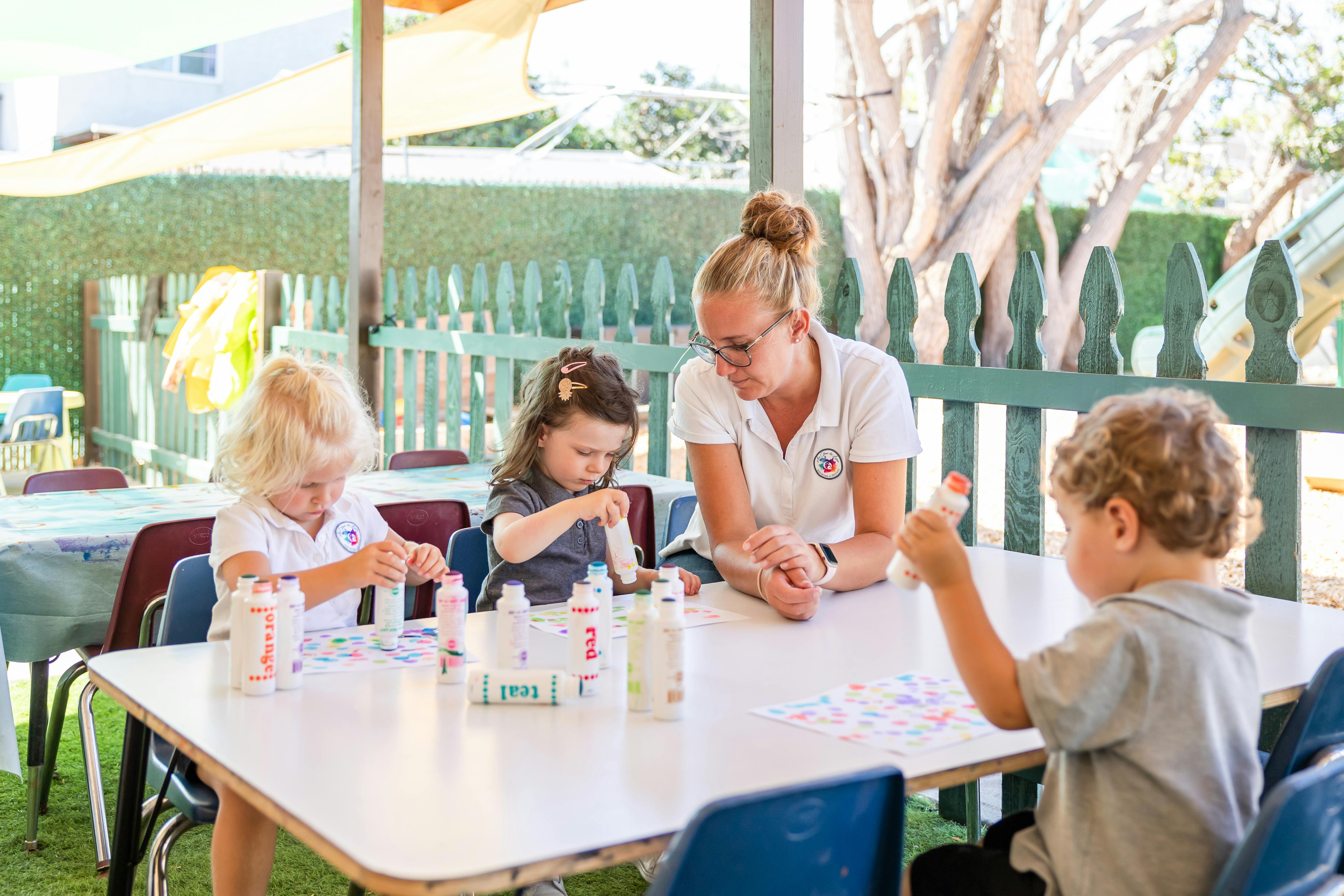 Adult and three children at a table with craft supplies