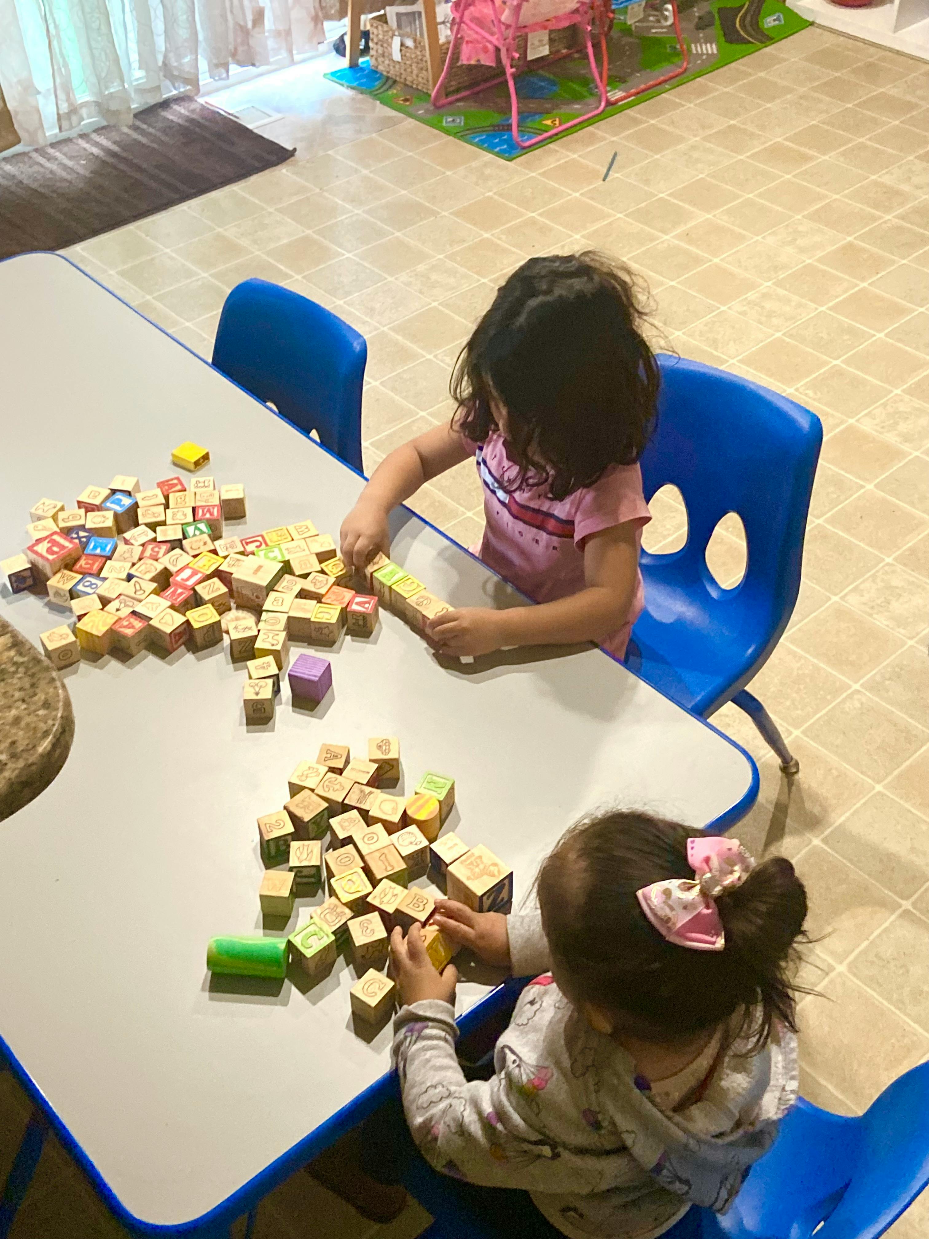 Two children playing with wooden blocks at a table