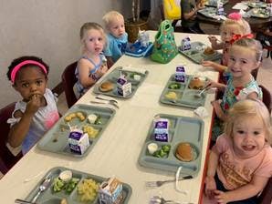 Children sitting at a table with lunch trays