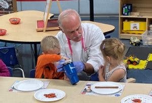 Adult helping two children with an activity at a table