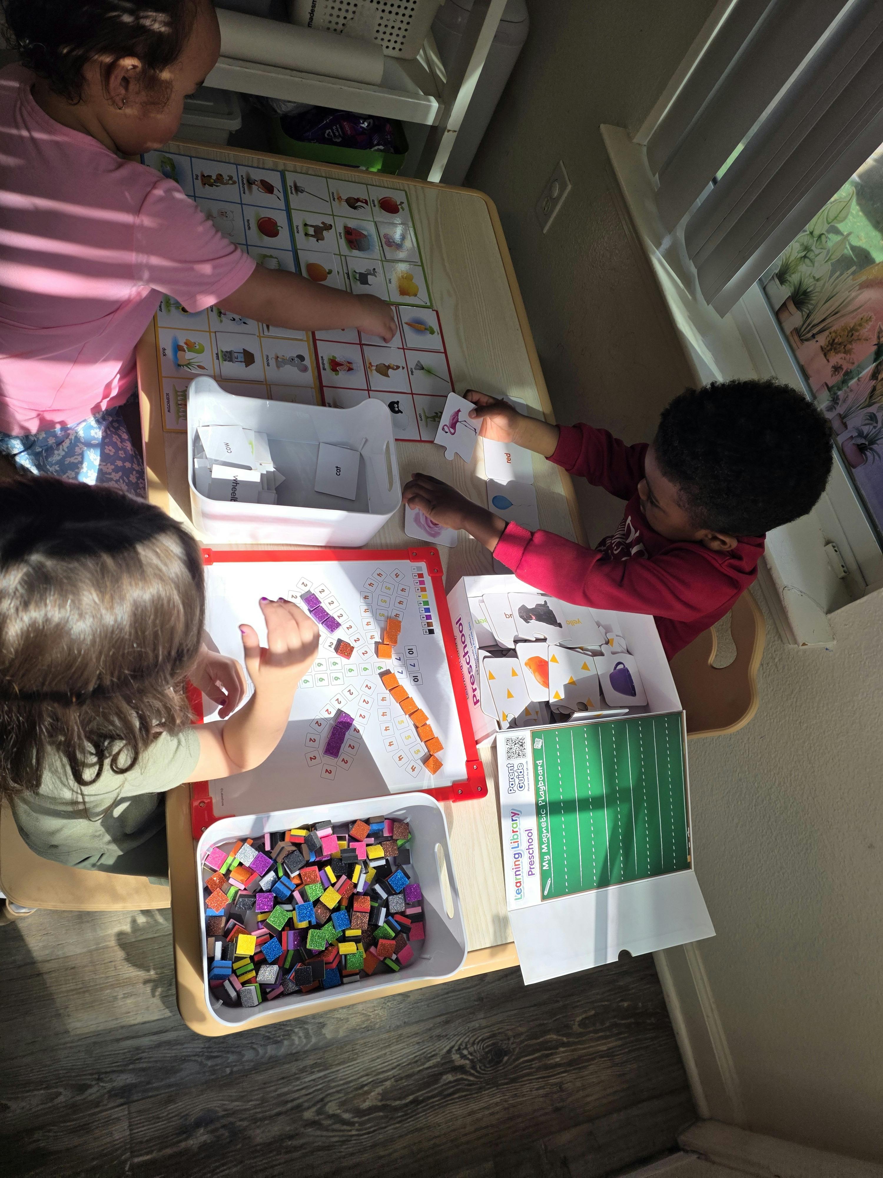 Three children playing with educational games and blocks at a table