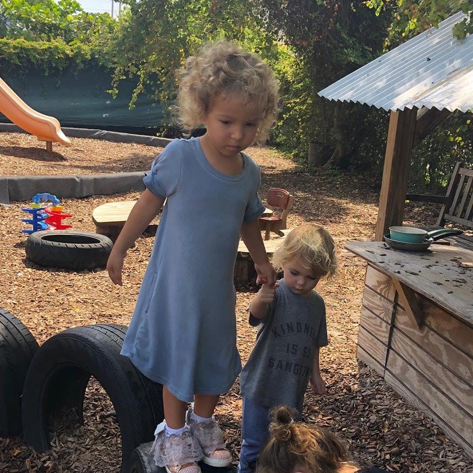 Two children playing outdoors, one standing on a tire