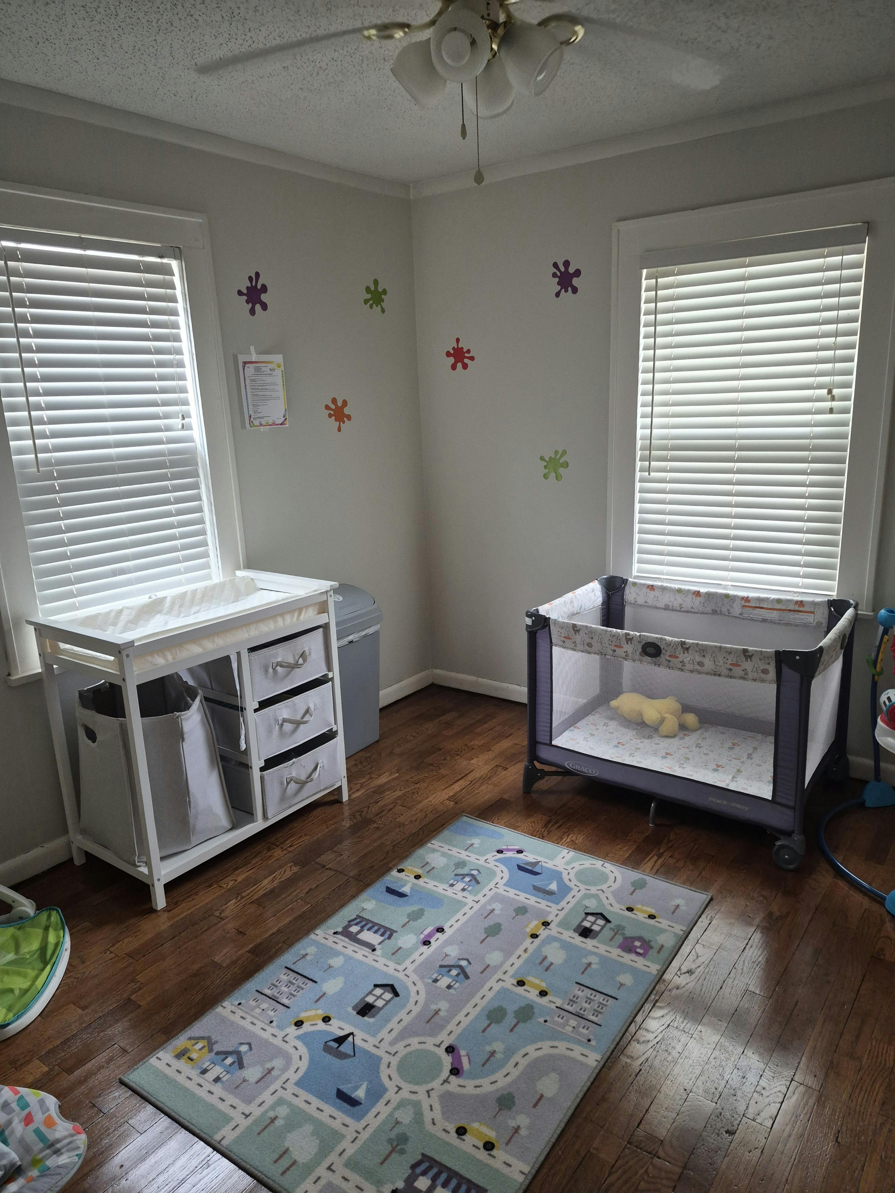 Baby nursery with changing table, playard, and city map rug