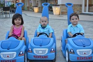 Three children in blue toy cars
