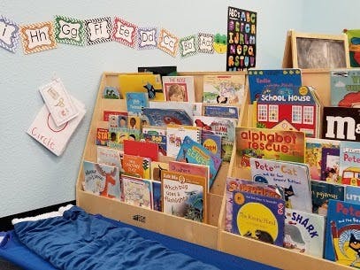 Children's books displayed on a wooden shelf in a classroom