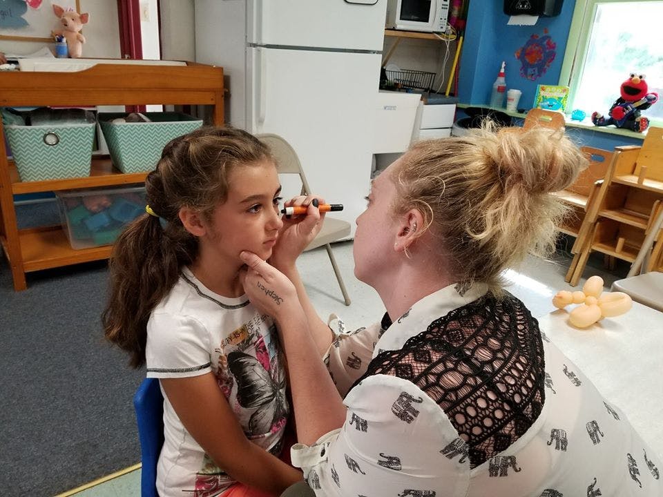 Person applying makeup to a child's face