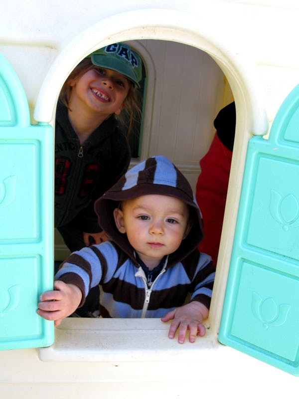 two children peeking out of a playhouse window