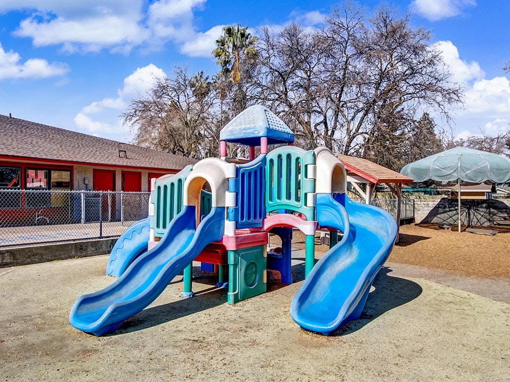 Colorful playground structure with multiple blue slides on a sunny day