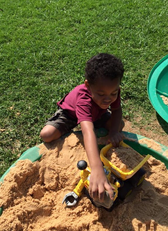 Child playing in a sandbox with a toy
