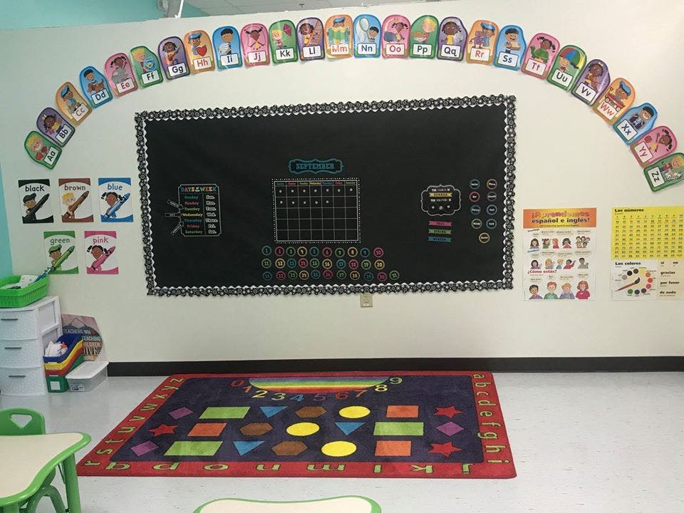 Classroom with a chalkboard, colorful rug, and decorations on the wall, a row of cutouts
