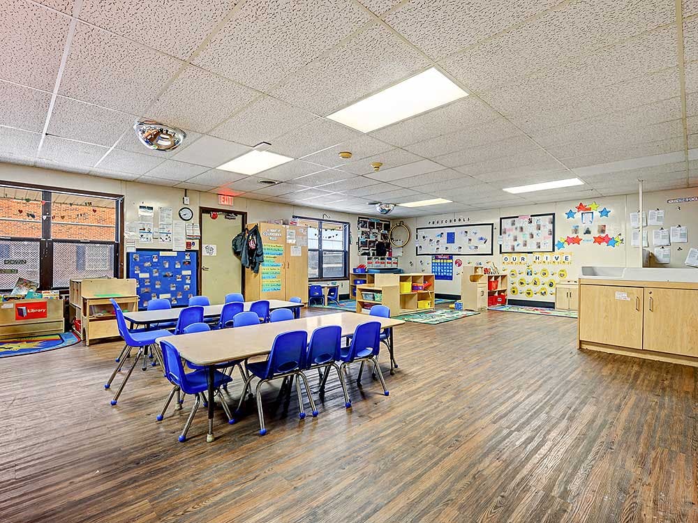 Empty classroom with tables, chairs, and learning decorations