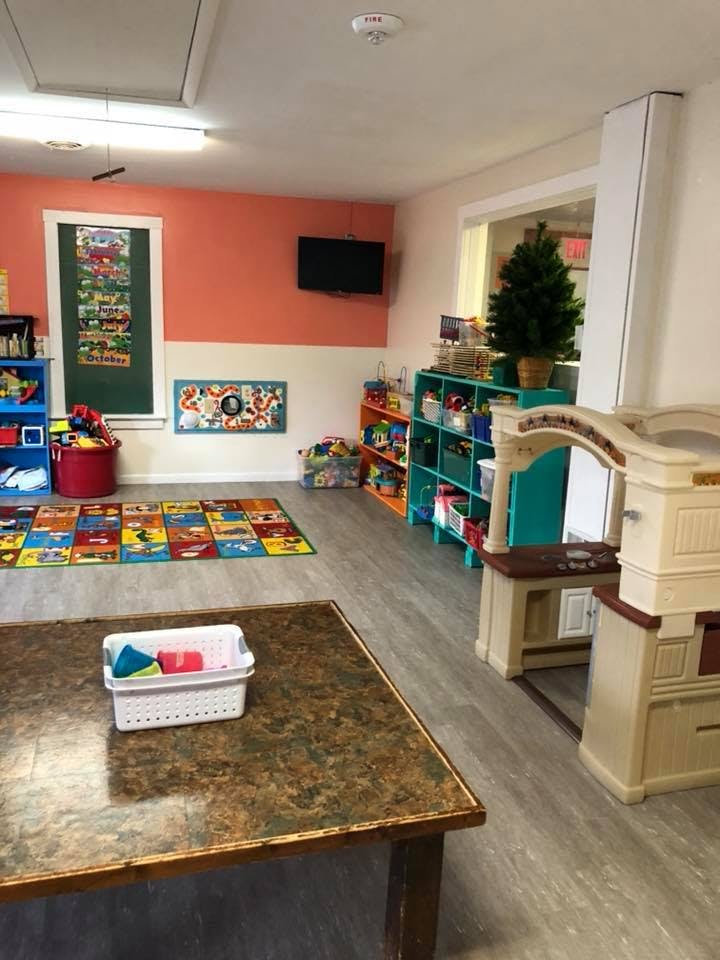 Playroom with colorful rug, shelves of toys, and play kitchen
