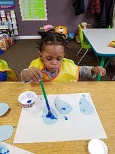 Child painting with blue paint on paper