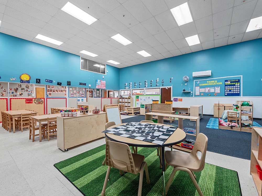 Empty classroom with small tables and chairs, and play areas