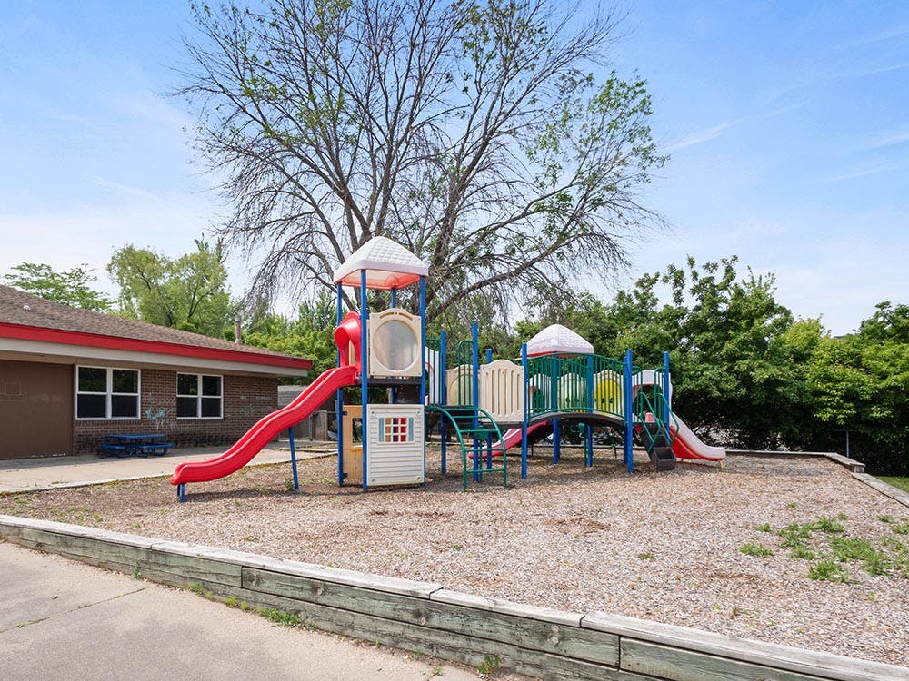 Colorful playground structure with slides and a connected building in the background