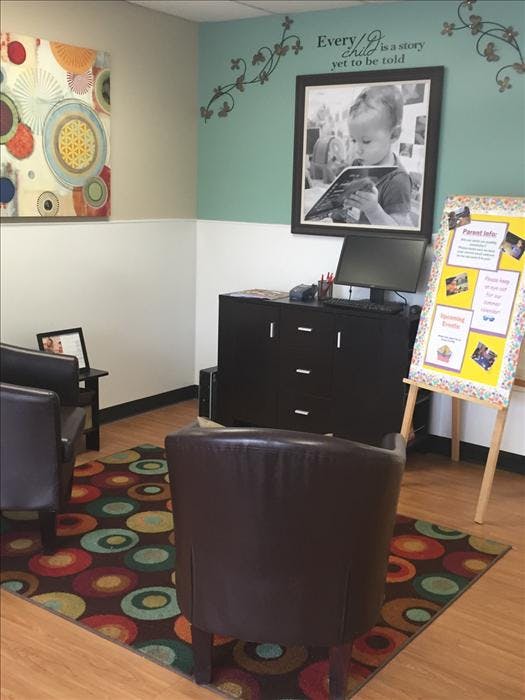 Waiting room with two chairs, computer desk, and child reading image on wall