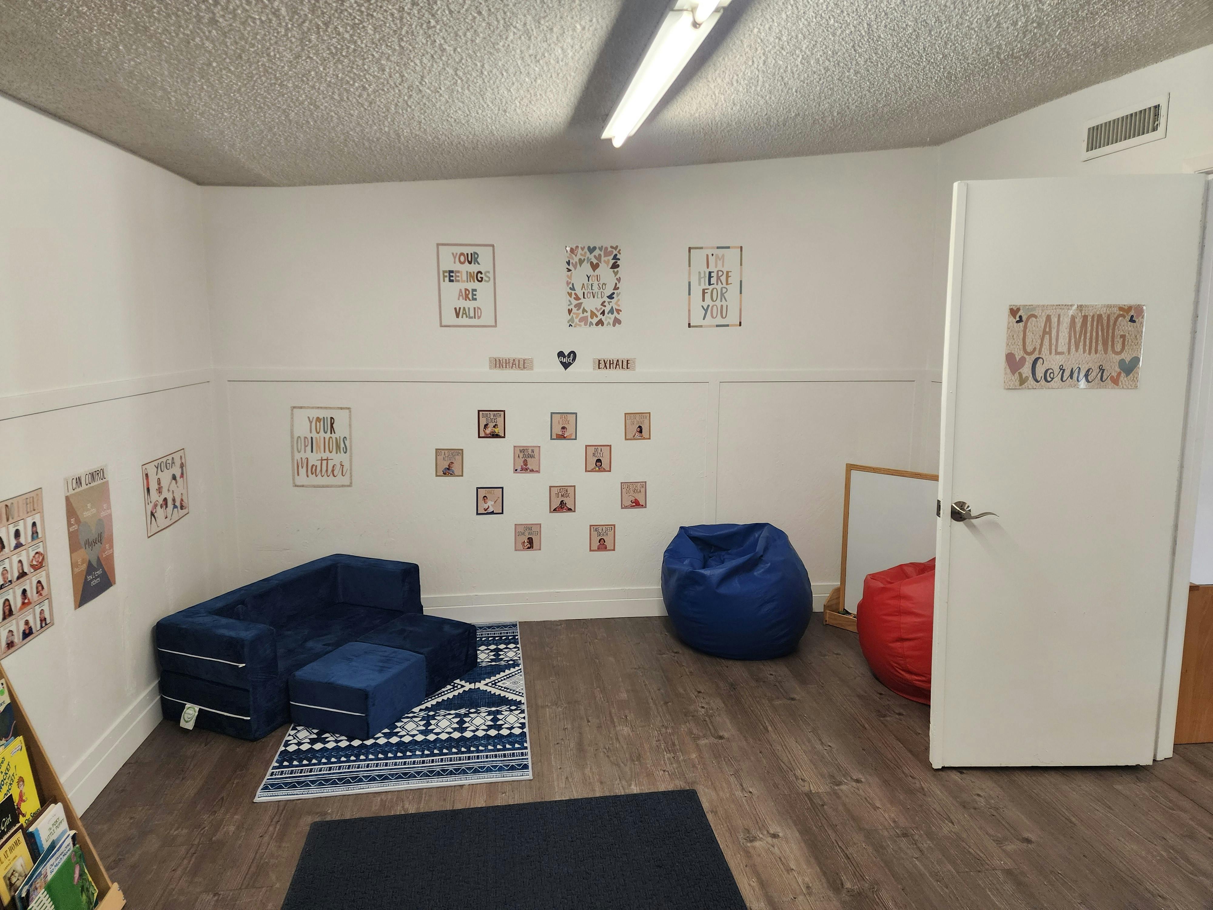 Room with blue sofa, bean bags, and wall decorations