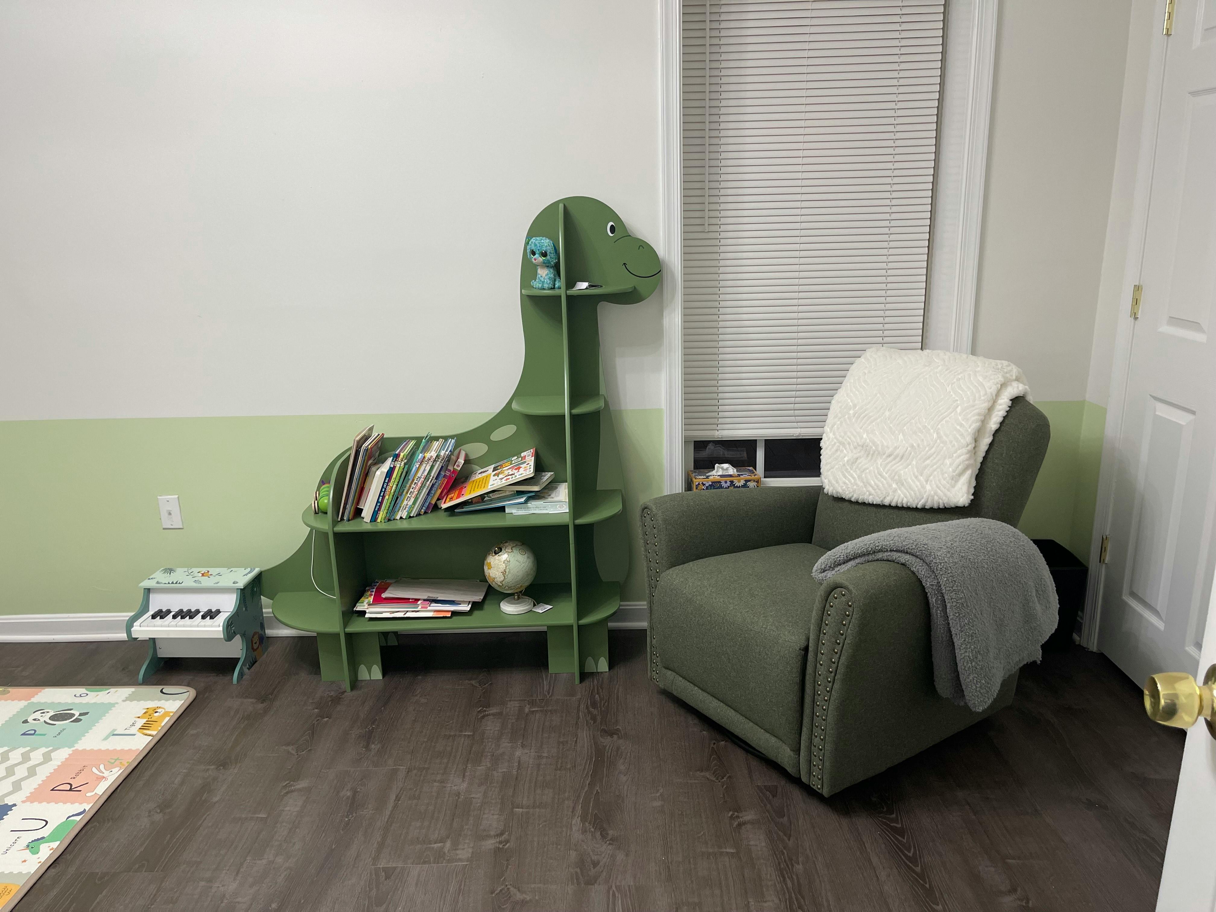 Green dinosaur-shaped bookshelf with books next to a green armchair