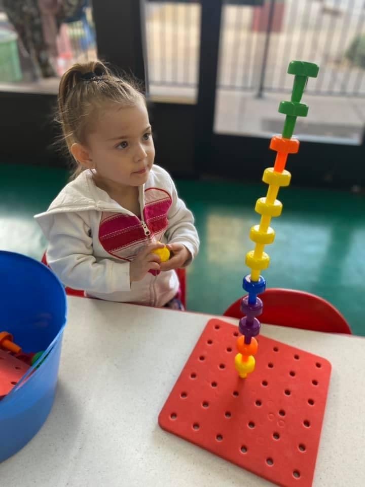 Child playing with a colorful stacking toy on a table
