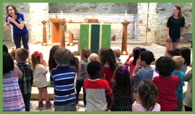 Two people with a group of children in a large room