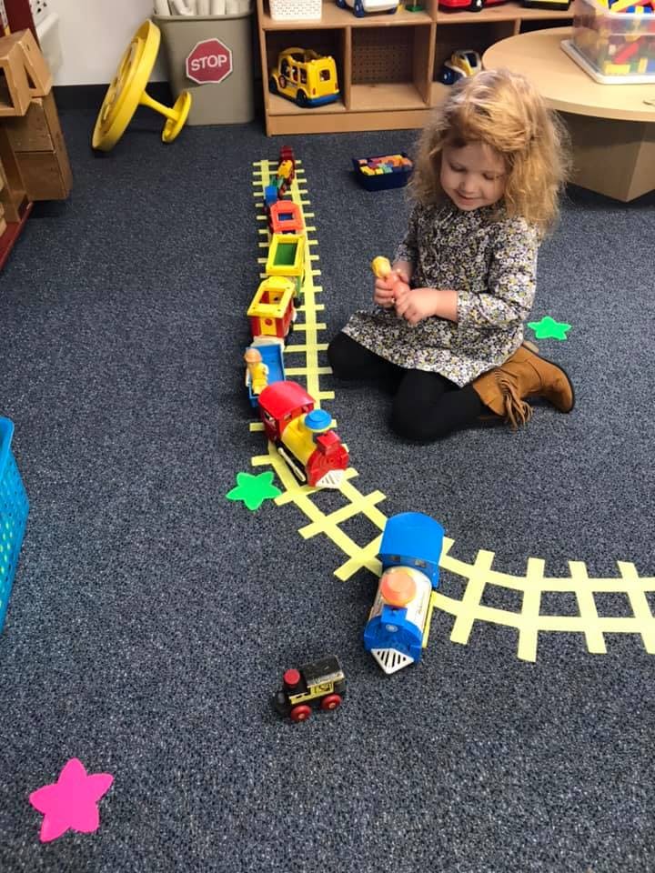 Child playing with a toy train on a track