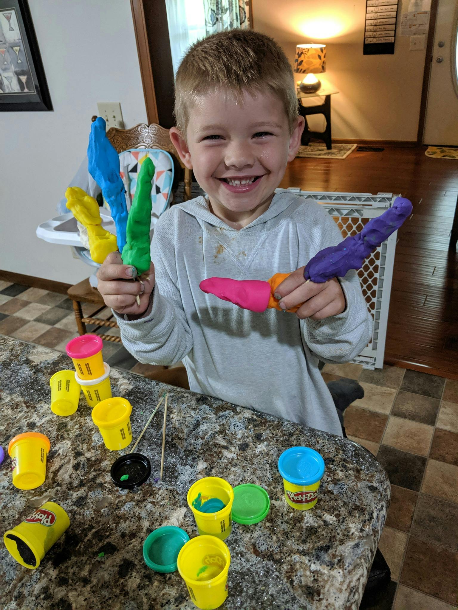 Child holding colorful playdough creations