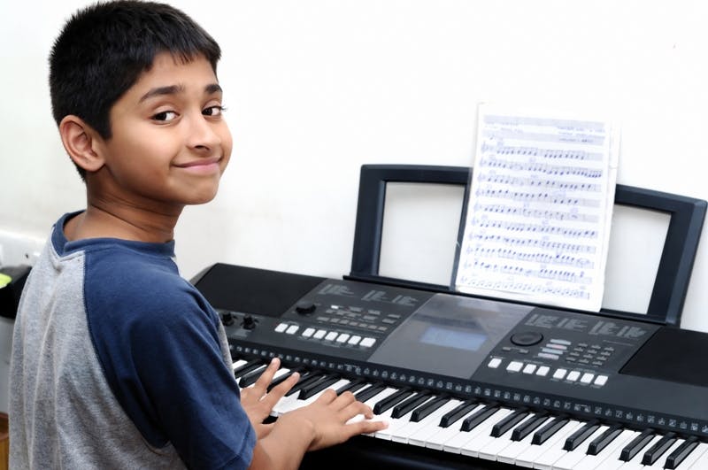 Child playing a keyboard with sheet music