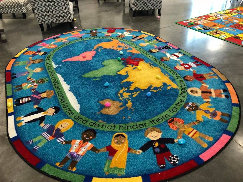 Round rug with a world map and diverse children holding hands around the border