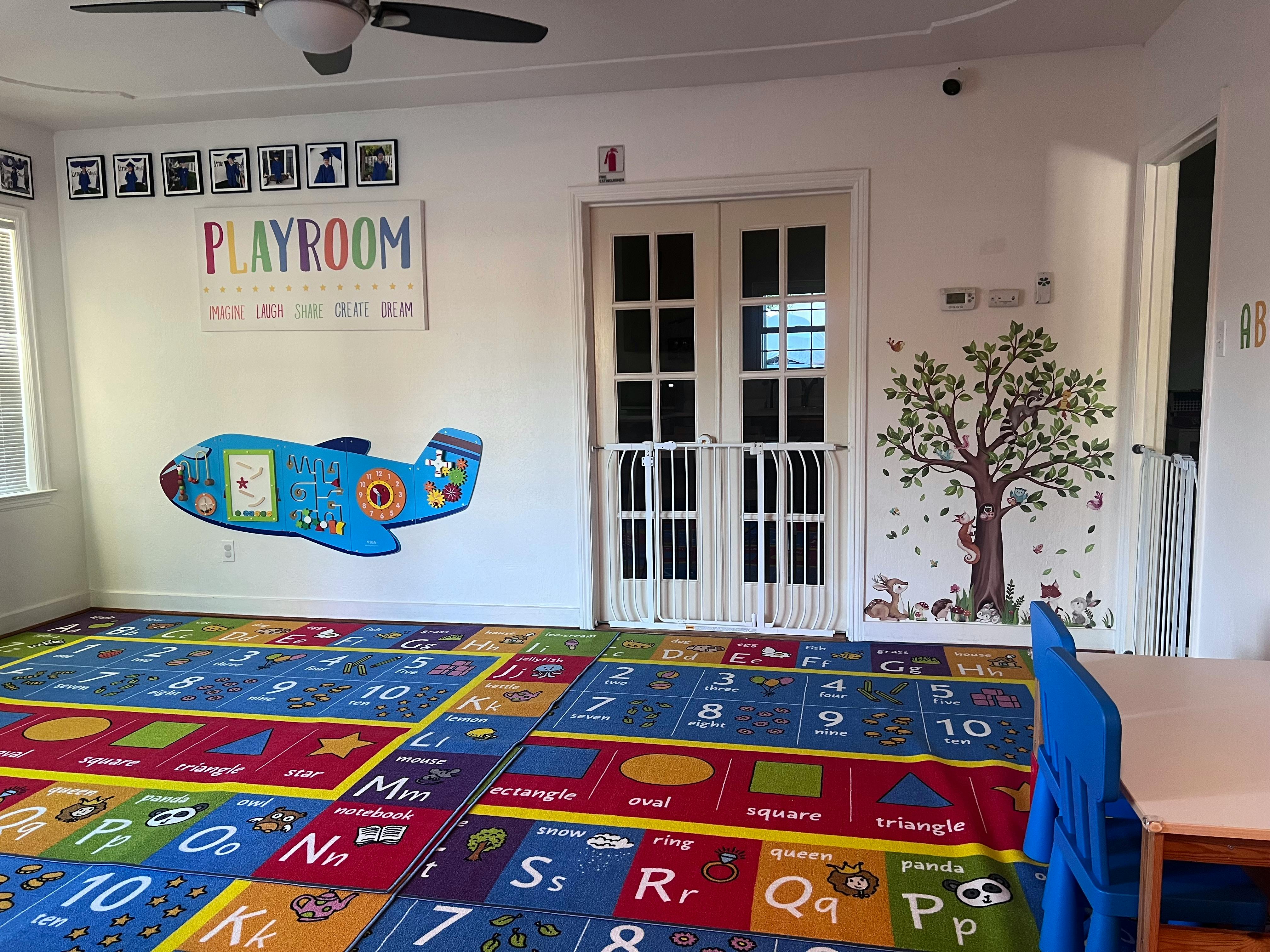 Playroom with colorful alphabet rug, airplane decoration, and tree mural