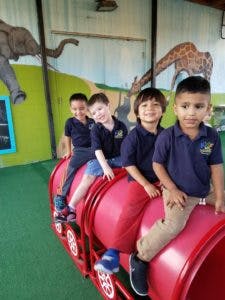 Four children sitting on a red play train