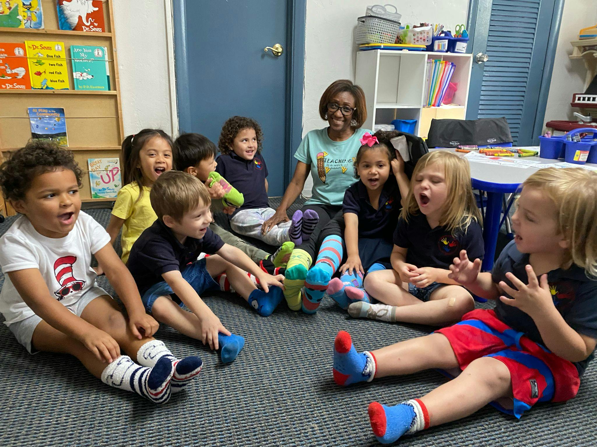 Adult and children sitting on the floor in a classroom