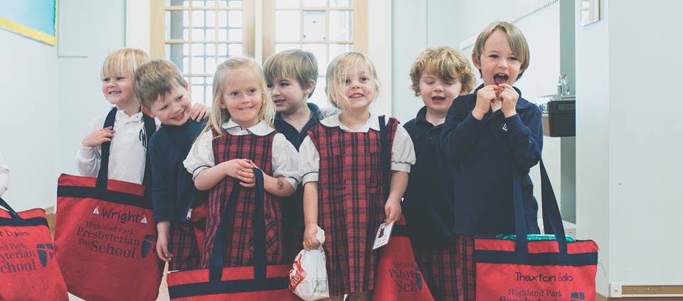 Group of children standing with red bags