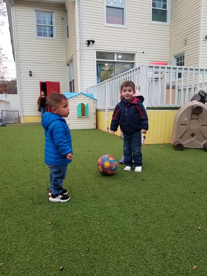 Two children playing with a ball on artificial grass