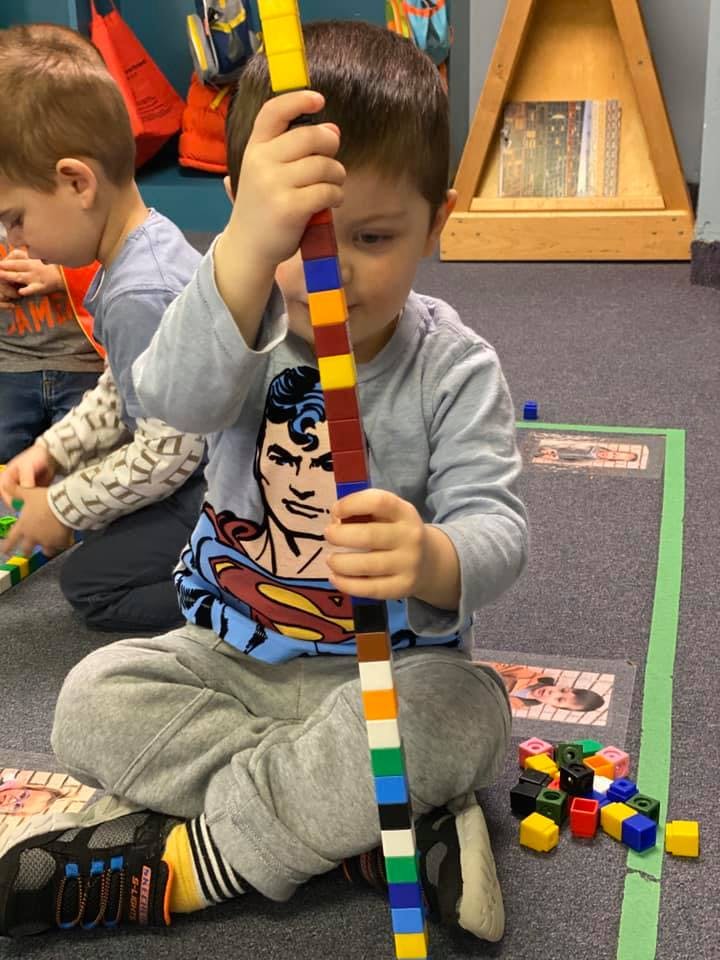 Child holding a long stick made of colorful interlocking blocks