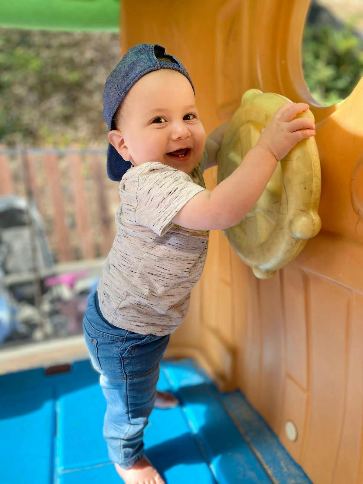Child in a blue hat playing with a yellow toy
