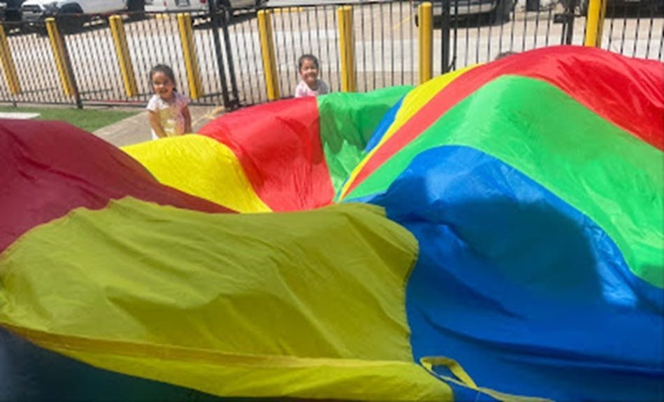 Two children playing with a colorful parachute