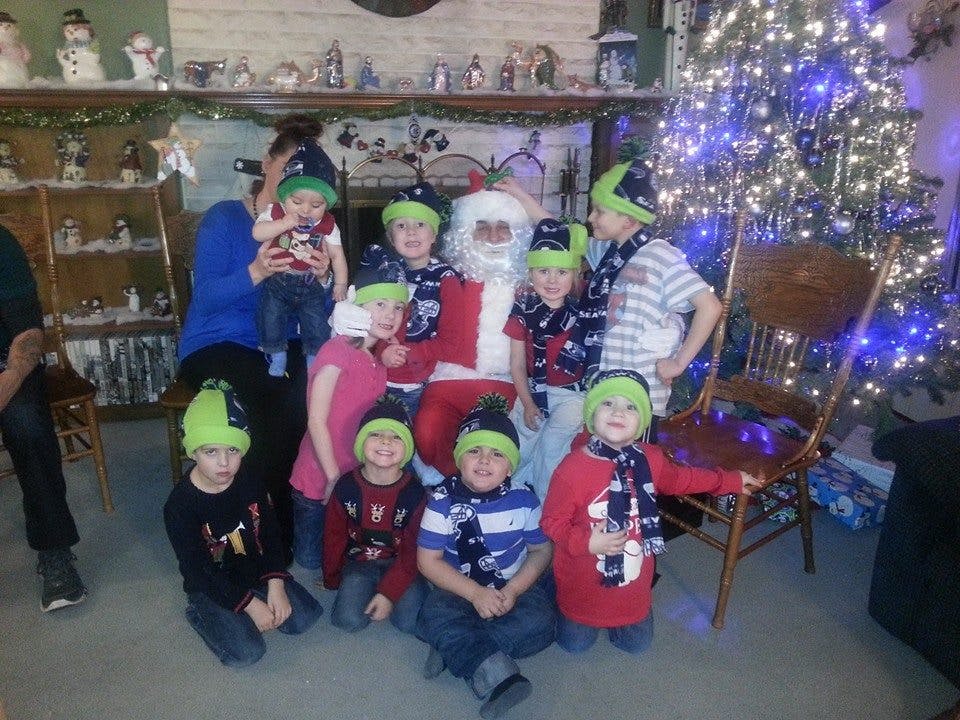 Santa Claus with a group of children wearing matching hats and scarves