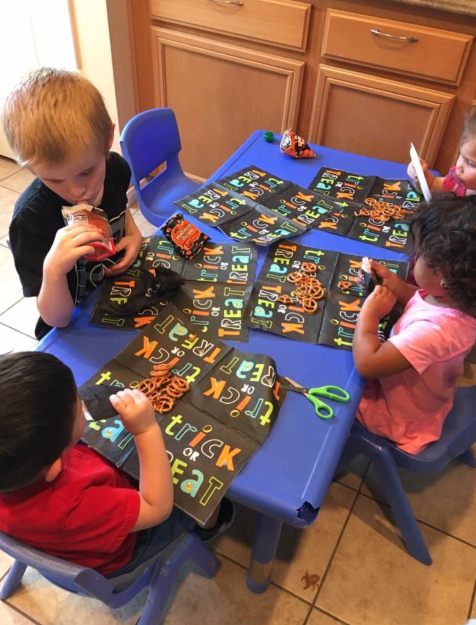 Three children at a table with Halloween-themed craft papers