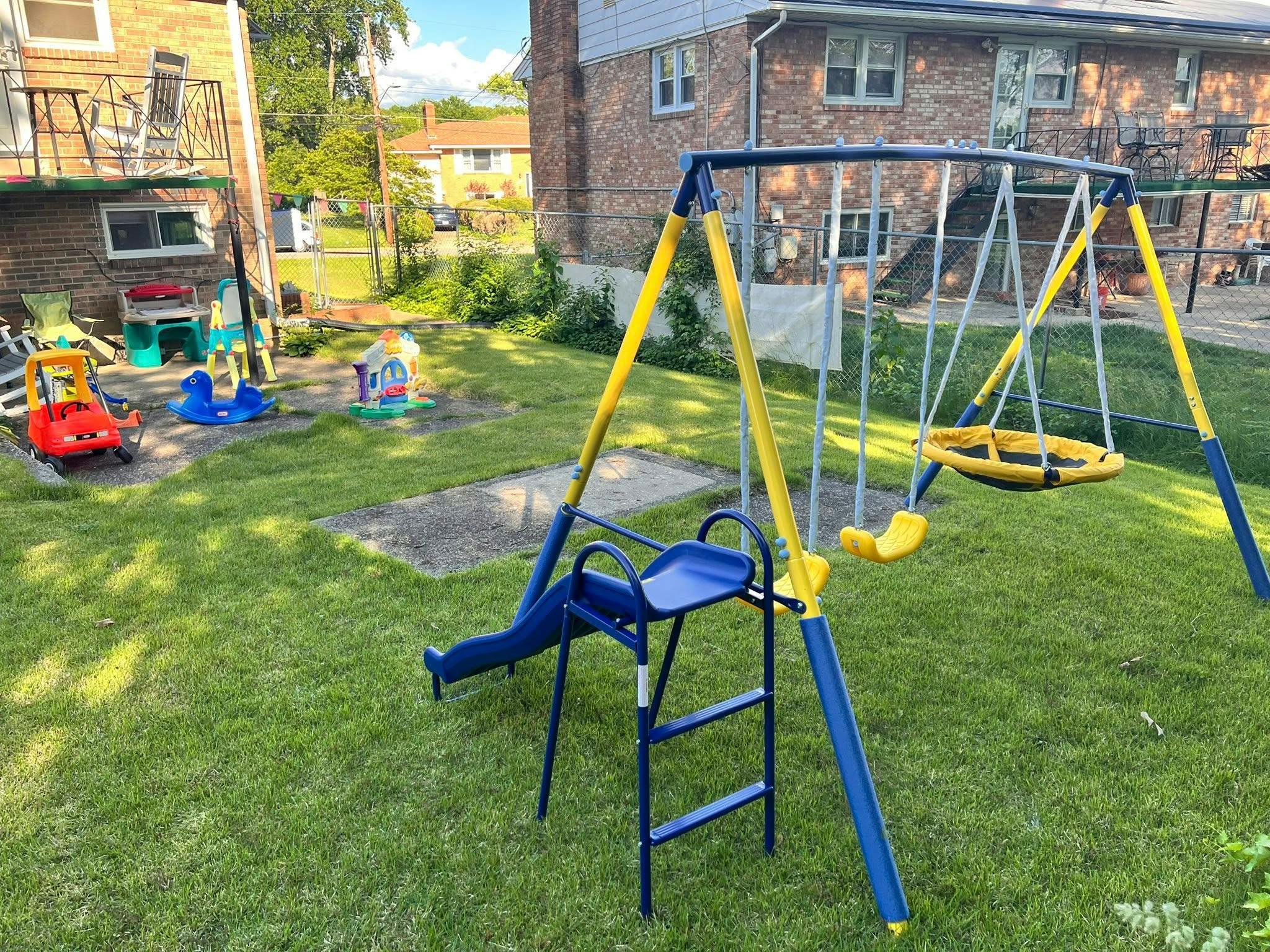 Backyard with a swing set, slide, and various toys on-ground toys
