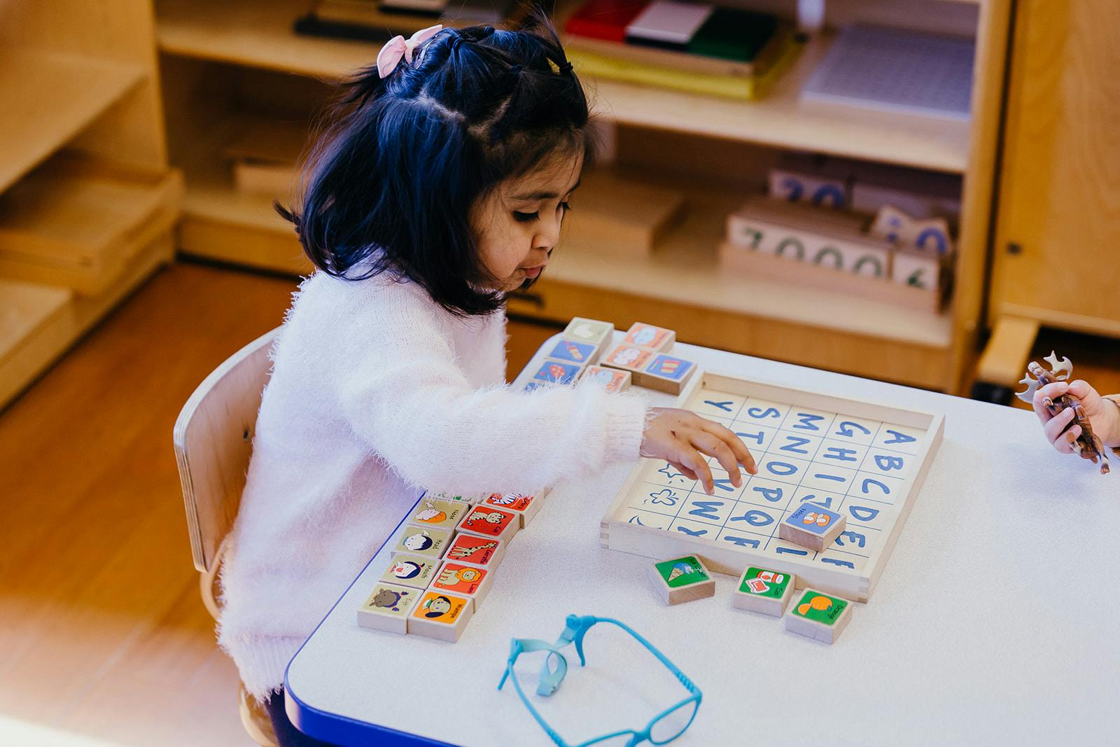 Child playing with alphabet blocks at a table