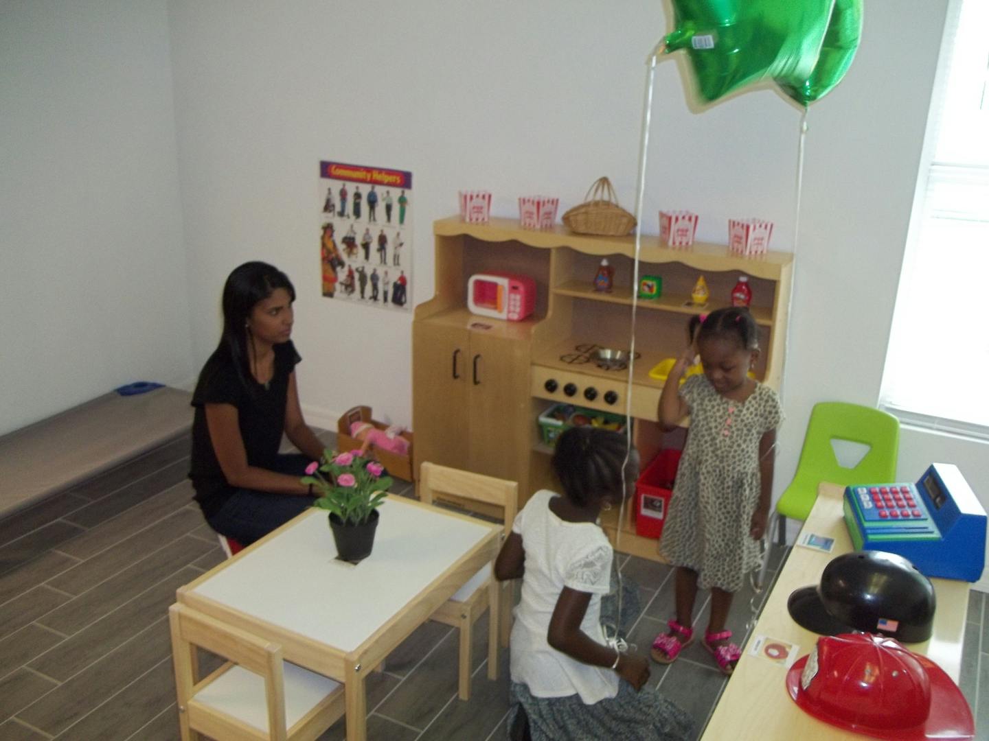 Adult and two children playing in a room with a toy kitchen