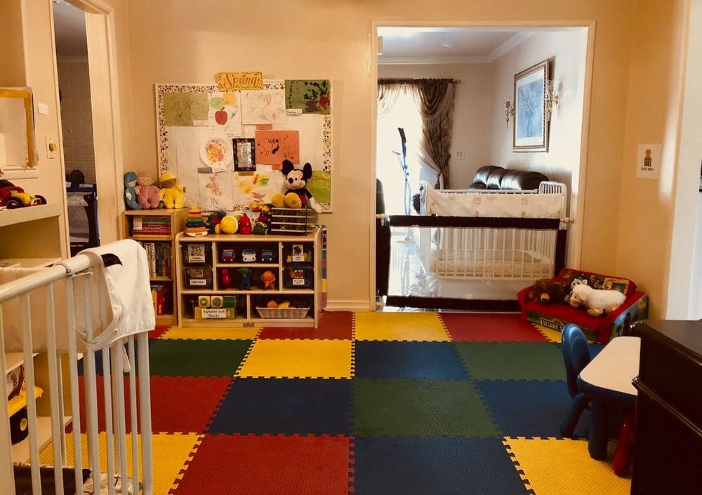 Playroom with colorful floor mats, shelves of toys, and a crib